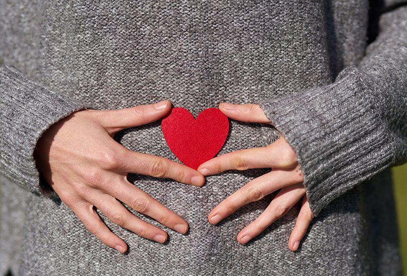 Women holding heart over abdomen